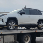 A white vehicle was photographed on the back of a tow truck