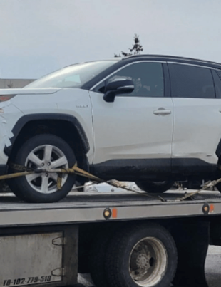 A white vehicle was photographed on the back of a tow truck